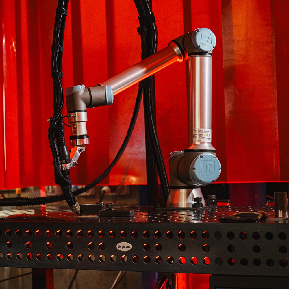 Cobot welding cell: robot arm, torch and clamped workpiece on a Siegmund welding table